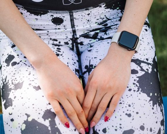 A smartwatch worn on a person's wrist with athletic leggings in an outdoor setting.